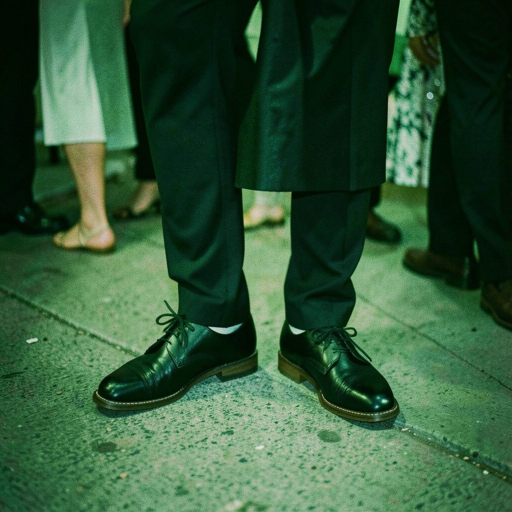 A pair of comfortable afterparty shoes beside dancing feet, warm low light and soft amber tones.